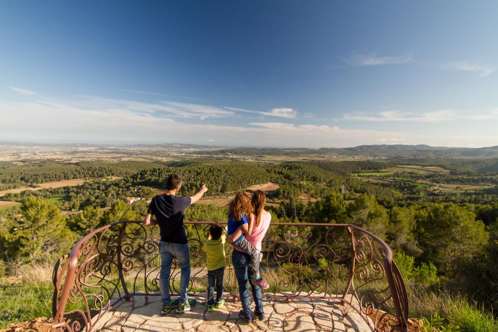 Family looking out from a viewpoint over the Penedès vineyards and forested hills