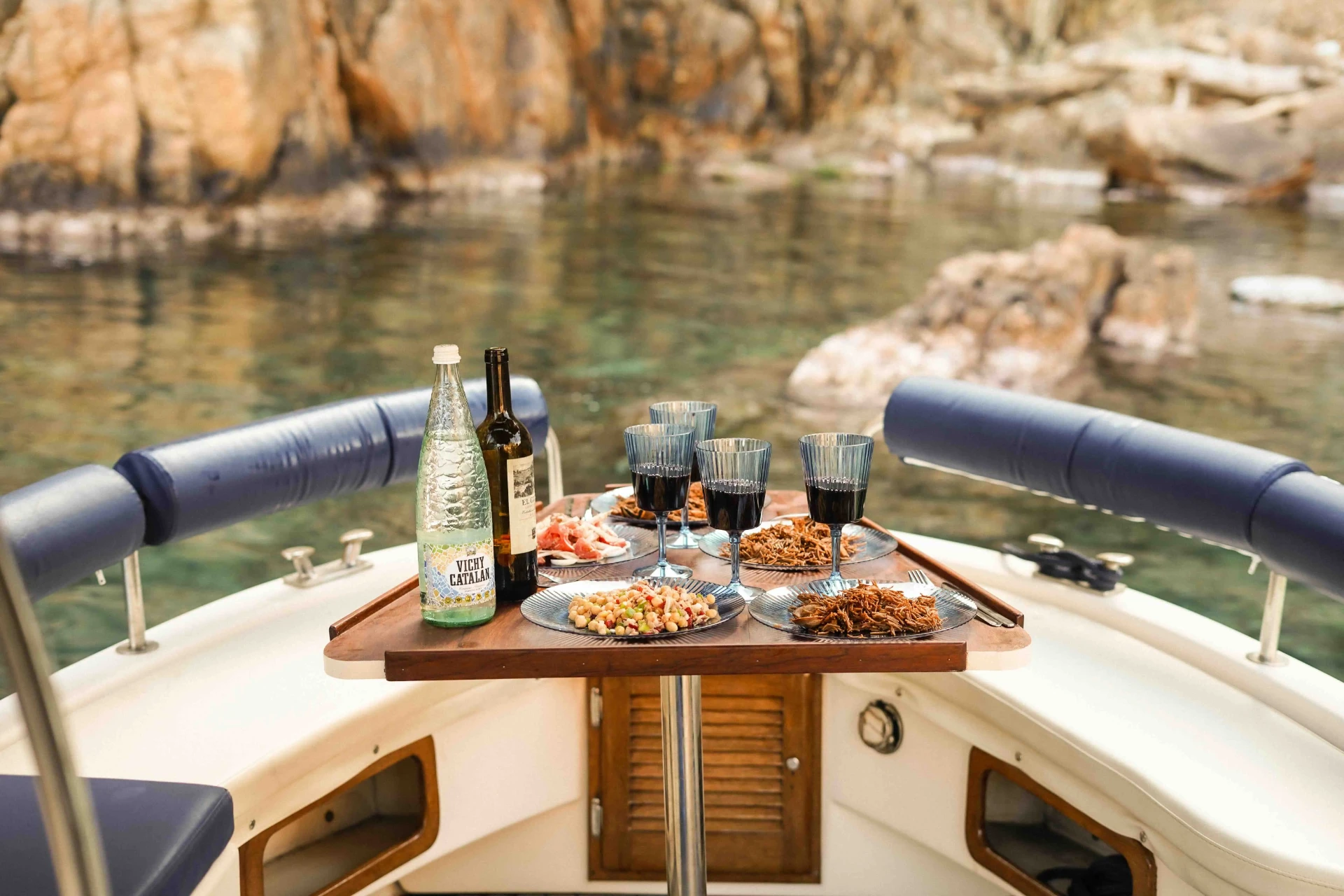 Wine and Catalan snacks served on the cockpit table of a private boat in a Costa Brava cove
