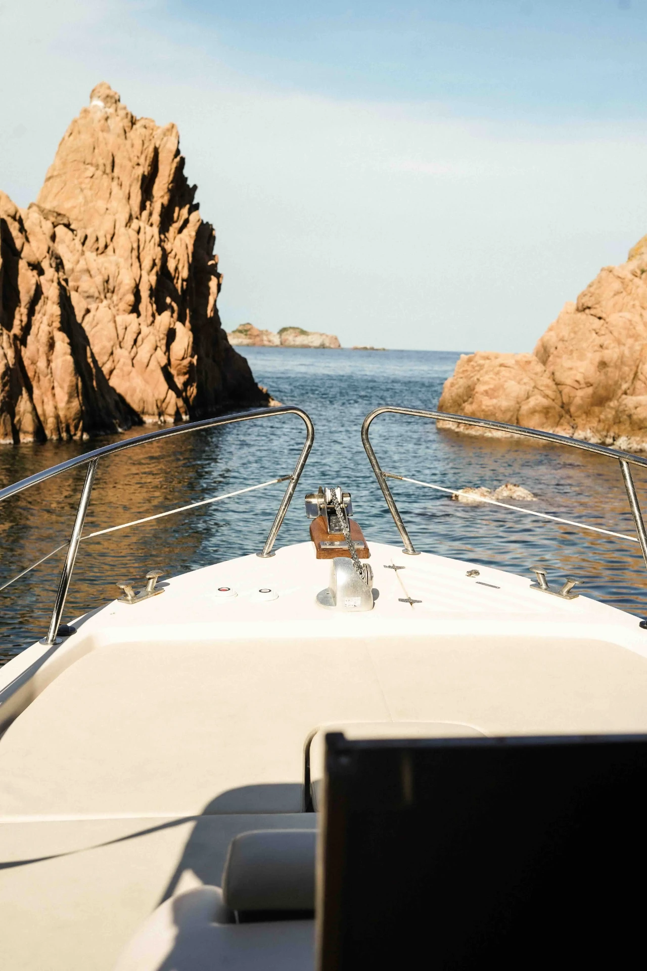 Private boat entering a hidden cala with red cliffs on the Costa Brava