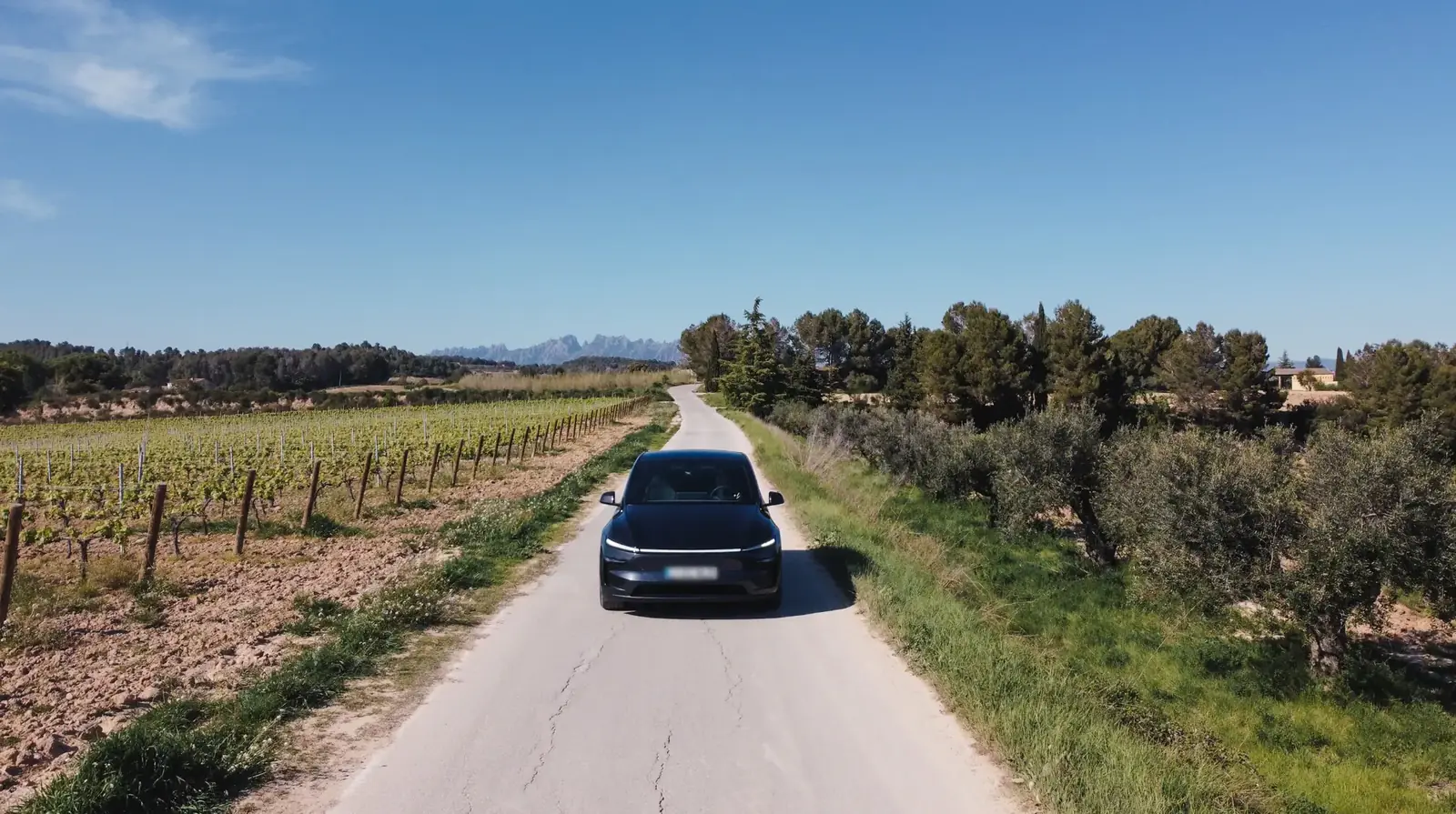 Premium 2026 Tesla Model Y on a vineyard road approaching Montserrat